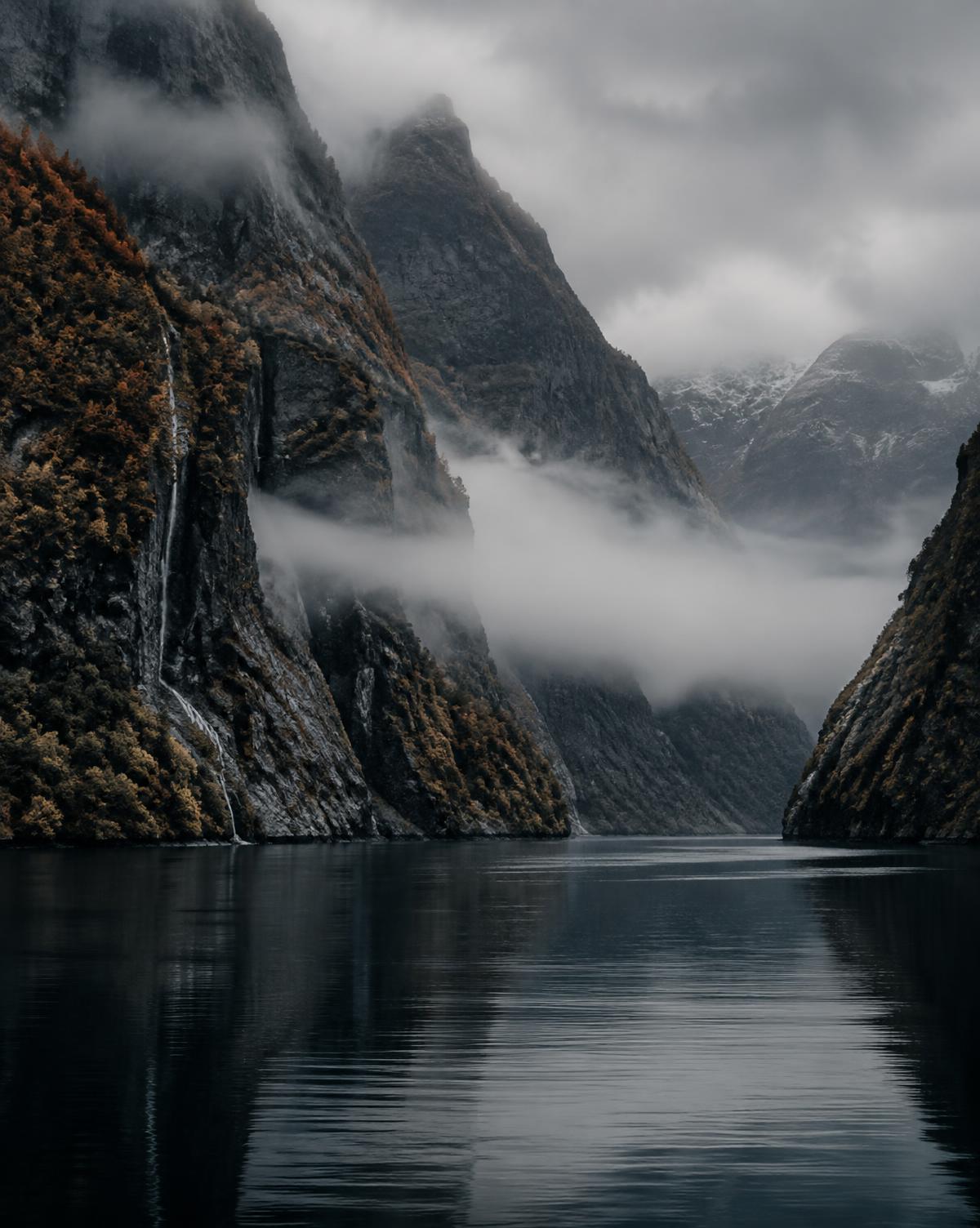 Nordisk fjord i dimma med branta bergssidor